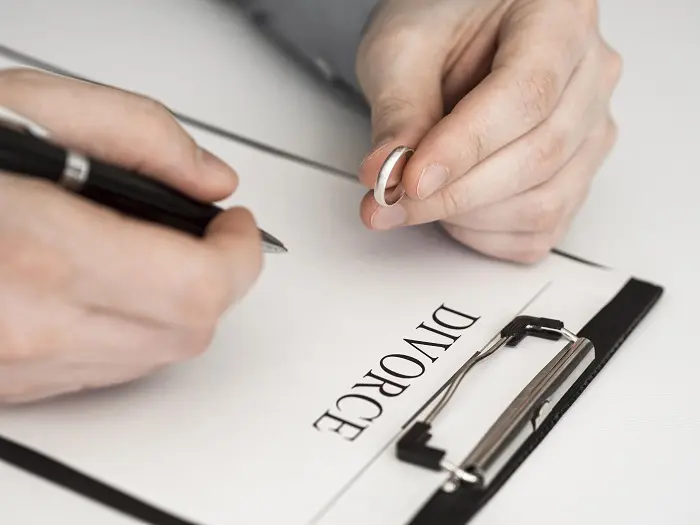 A man holds a ring and fills out divorce forms