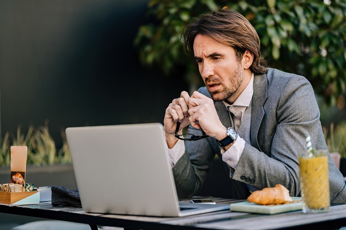 A man sits at a table and looks at a laptop